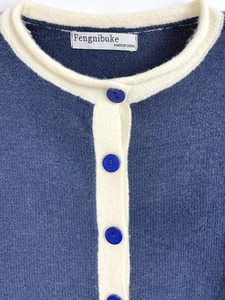 Detailed macro view of navy knit cardigan with contrast collar and brand neck label