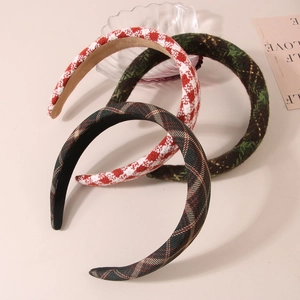 Close-up of three checkered fabric headbands in red and green patterns for women