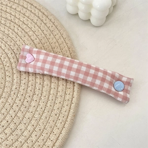 Detail of pink gingham fabric cable organizer with heart and round button accents
