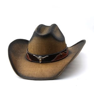 Detail of a brown cowboy hat featuring a silver bull head logo on a leather band