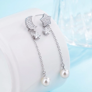 Macro view of sterling silver star and moon dangle earrings with cubic zirconia and pearls