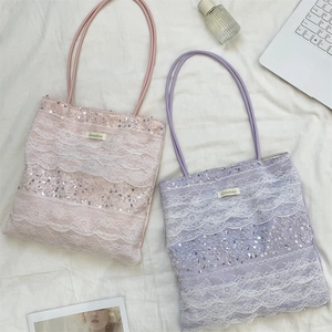 Détail de sacs fourre-tout en dentelle mauve et rose avec paillettes et motifs floraux