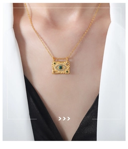 Detail of 18k gold evil eye rectangular pendant necklace featuring green gemstone