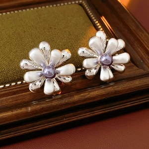 Macro detail of vintage 18k gold plated flower earrings with purple pearl center