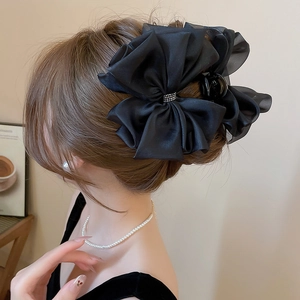 Dettaglio di una grande clip per capelli a fiocco nero con strass in un'acconciatura elegante