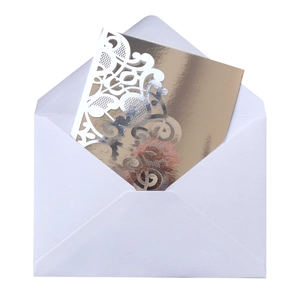 Detailed view of white envelope and gold laser-cut floral wedding invitation card