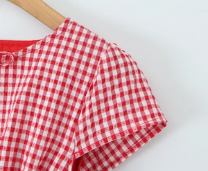 Detail of red plaid puff sleeves and ruffled neckline on cotton blend fabric