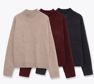 Flat lay of oatmeal, burgundy, and dark grey knit sweaters showing ribbed textures