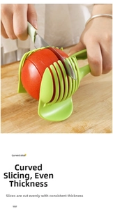 Close-up of a green multi-slot tomato slicer guide on a wooden board with a red tomato