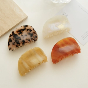 Flat lay of four tortoiseshell and pearlescent acetate hair claws on a minimalist background