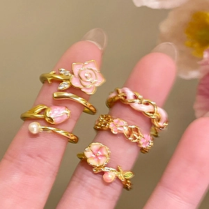 Detail of 18k gold plated floral rings with pink enamel flowers and zircon stones