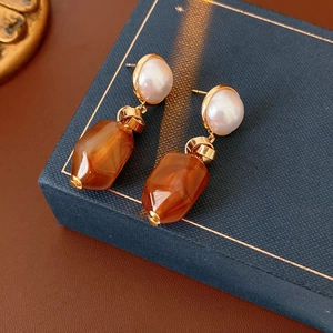 Close-up of vintage pearl and brown faceted resin drop earrings on a jewelry box