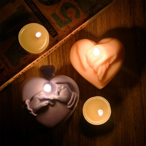 Macro view of pink and purple heart-shaped candles with hand-holding 3D relief texture