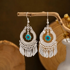Ethnic bohemian silver tassel earrings with turquoise beads hanging on a wooden branch