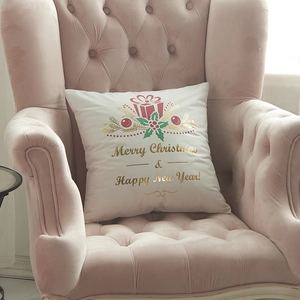 Christmas cushion cover with golden prints on pink velvet chair in festive setting