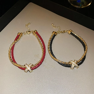Détail du bracelet double couche en cuir et chaîne dorée avec charme X en zircon
