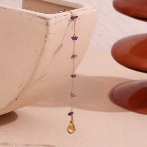 Detail of 18K gold plated chain with purple amethyst stones on ceramic plate