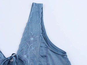 Vue détaillée de la broderie florale et du satin sur l'épaule de la robe courte bleue