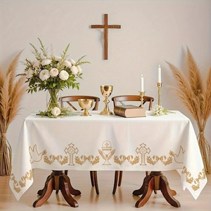 Close-up of white altar cloth featuring gold religious embroidery on a wooden table