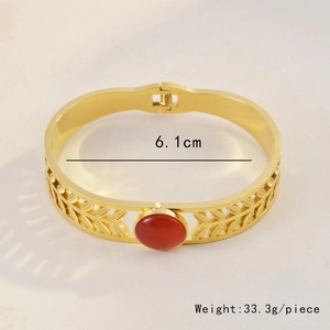 Detailed close-up of golden leaf pattern bracelet with red stone inlay and size specs