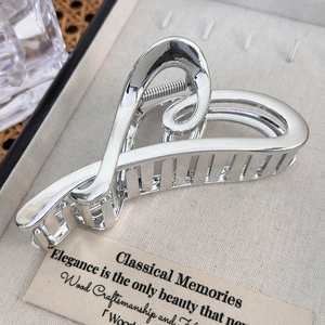 Close-up of a silver heart claw clip with a hollow design and polished metallic finish