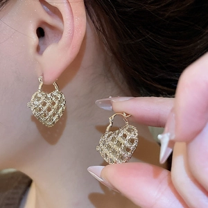 Detailed close-up of hollow gold heart earrings featuring a unique mesh metal texture