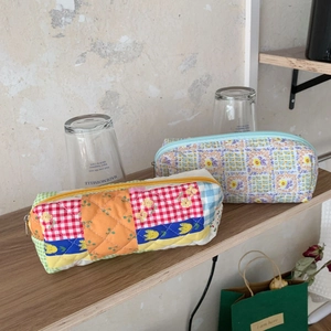 Detailed view of quilted patchwork and floral fabric pencil cases on a wooden shelf