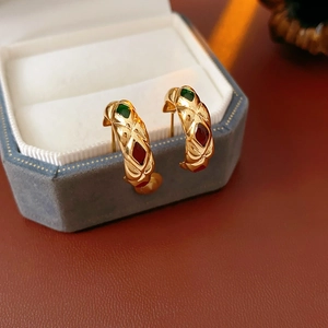 Detail of vintage gold C-shape earrings with red and green gems in a blue velvet box