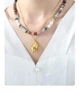 Close-up of a layered beaded pearl necklace with a golden conch pendant on a model