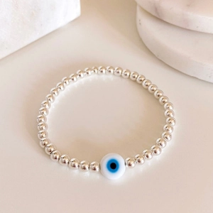 Silver beaded bracelet featuring a Turkish Evil Eye charm on a minimalist marble background
