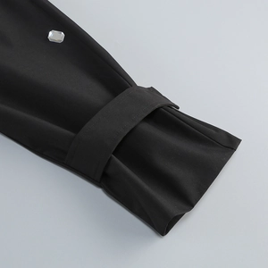 Détail d'une manche de robe de tailleur noire avec cordon assorti et un strass carré