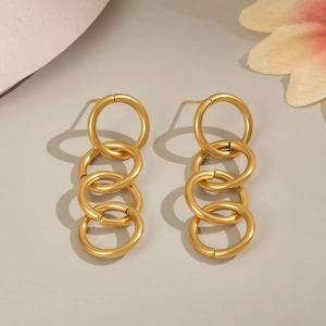 Macro shot of 18K gold plated interlocking circular chain drop earrings on a grey surface