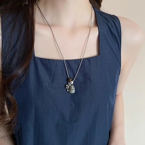 Close-up of a silver tassel necklace with tiger eye stone on a model's neck