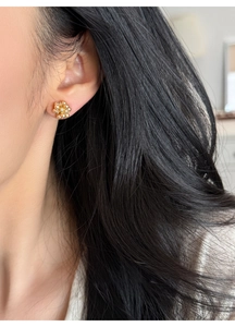 Close-up of golden floral pearl earrings with rhinestones on a female model