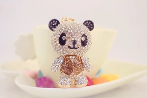 Macro detail of golden panda keychain with sparkling rhinestones and black enamel accents