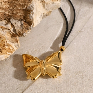Collana con ciondolo a farfalla dorata con cordino nero su sfondo di pietra naturale