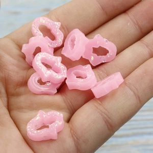 Pink resin Hamsa Hand opal beads with glitter finish held in palm for DIY jewelry
