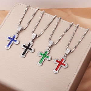 Detail of four cross necklaces with blue black green and red crystals on a display case