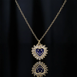 Golden necklace with blue enamel heart pendant and zircon smile face on black background