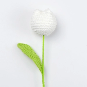 Handmade crochet white tulip flower with green stem and leaf on a clean white background