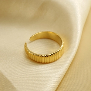 Macro detail of adjustable golden ring featuring elegant vertical ribbed texture on silk