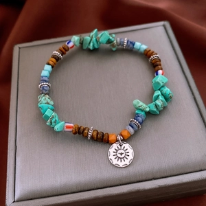 Détail du bracelet en perles vintage avec pendentif totem soleil sur boîte à bijoux