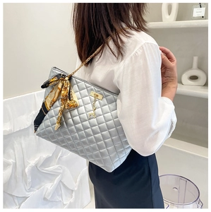 Detail of silver quilted shoulder bag with golden deer charm and printed silk scarf