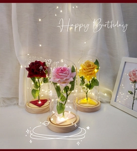 Close-up of LED rose flower glass dome with wooden base and fairy lights for gifts