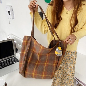 Detailed shot of large capacity plaid wool tote bag with cute plush penguin charm