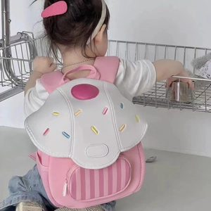 Pink cartoon cake-shaped kids backpack with embroidery shown on toddler's back