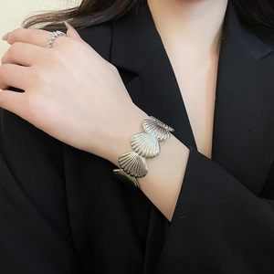 Close-up of stylish silver shell bracelet and paved diamond ring on a wrist with suit
