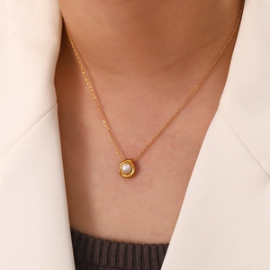 Close-up of a gold stainless steel necklace featuring a round white pearl pendant charm