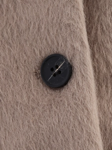 Detailed close-up of wool blend fabric and black button on camel cropped jacket