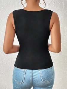 Top de punto negro entallado de un hombro visto desde atrás con jeans azules